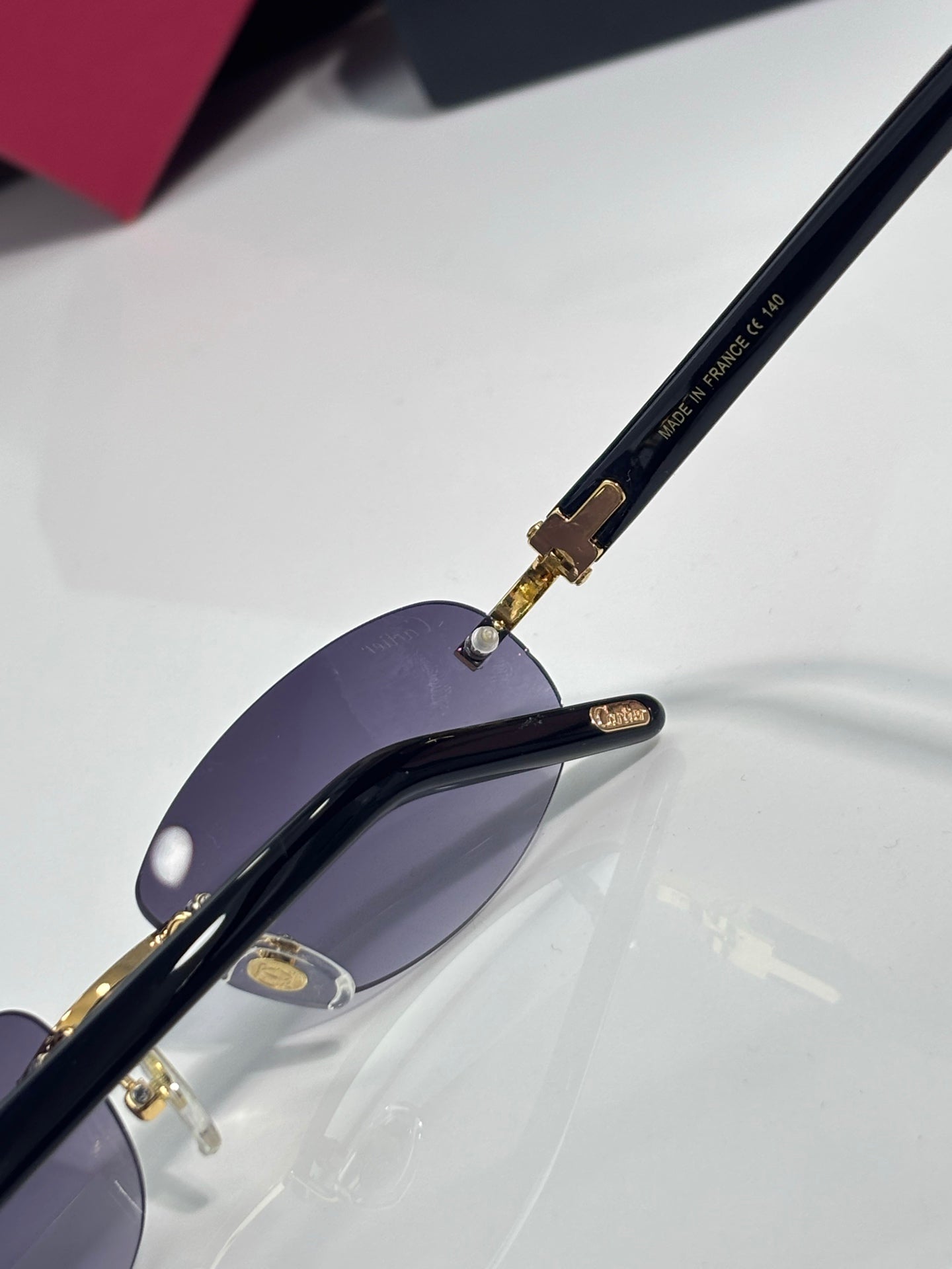 Cartier sunglasses with dark purple lenses and gold-trim temples, close-up