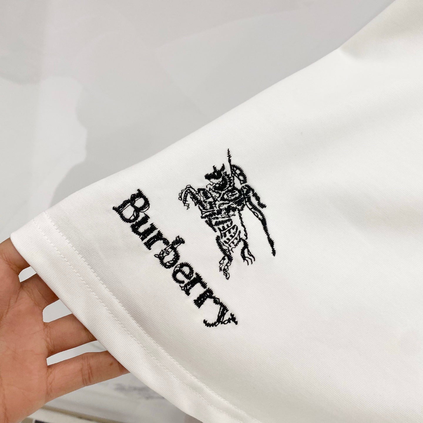 White Burberry T-shirt sleeve close-up with black horse emblem and Burberry text