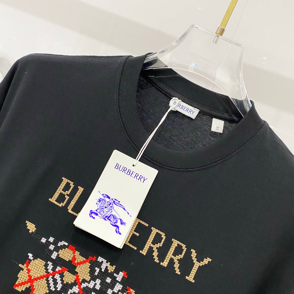 Black short-sleeve T-shirt with gold Burberry text and multicolor emblem, tags attached