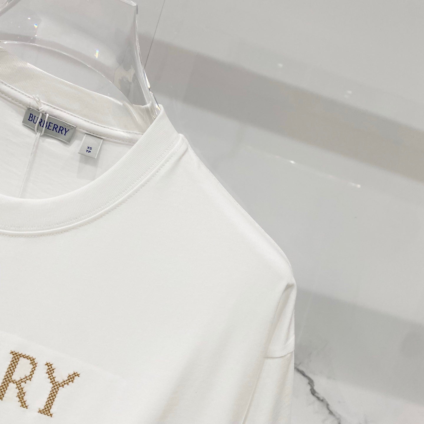 White Burberry T-shirt shoulder and neckline close-up on a hanger
