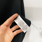 Black T-shirt fabric with Burberry care label held in hand