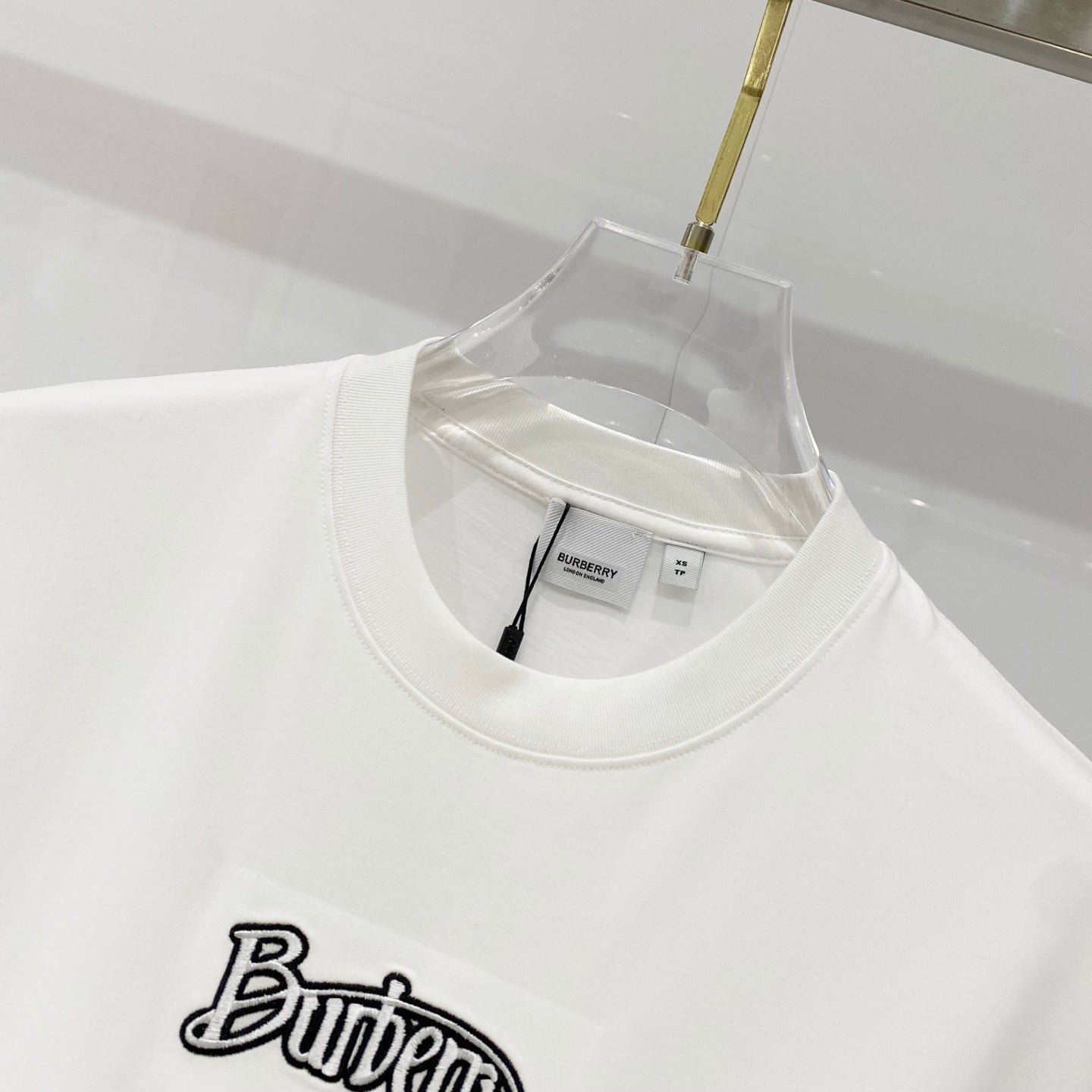 White short-sleeve T-shirt neckline with black “Butter” graphic logo patch