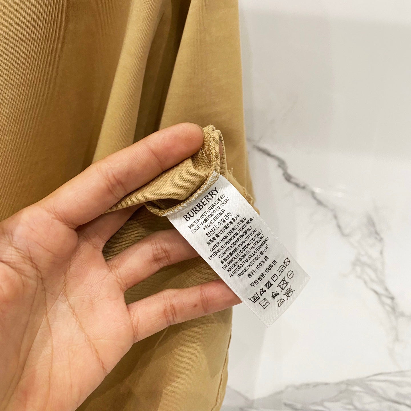 Tan T-shirt with care label tag shown near the side seam