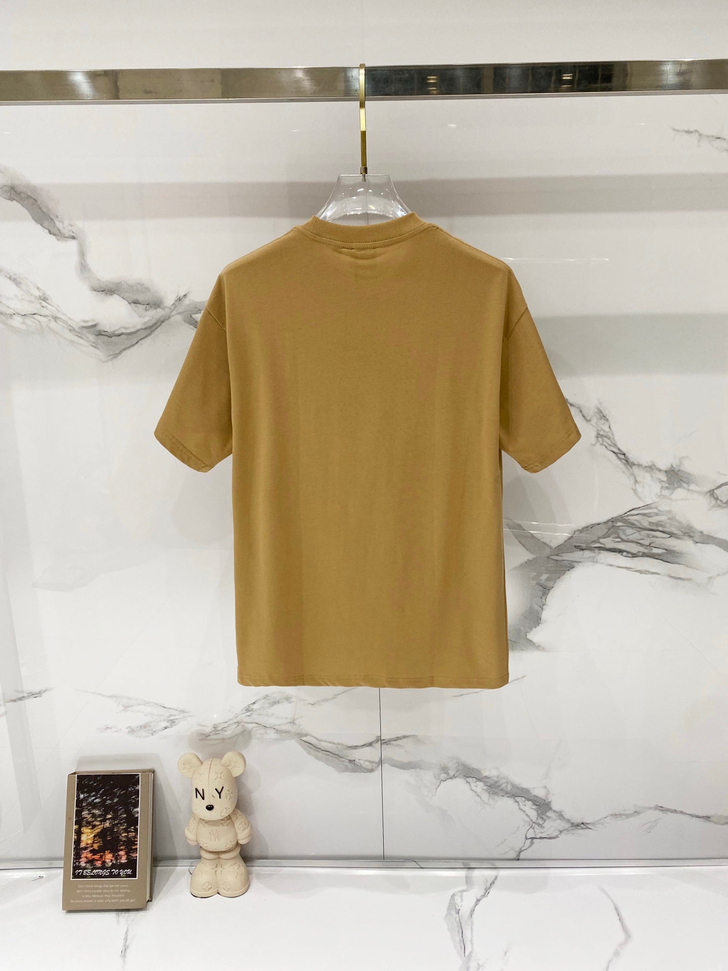 Tan short-sleeve T-shirt back view on a hanger