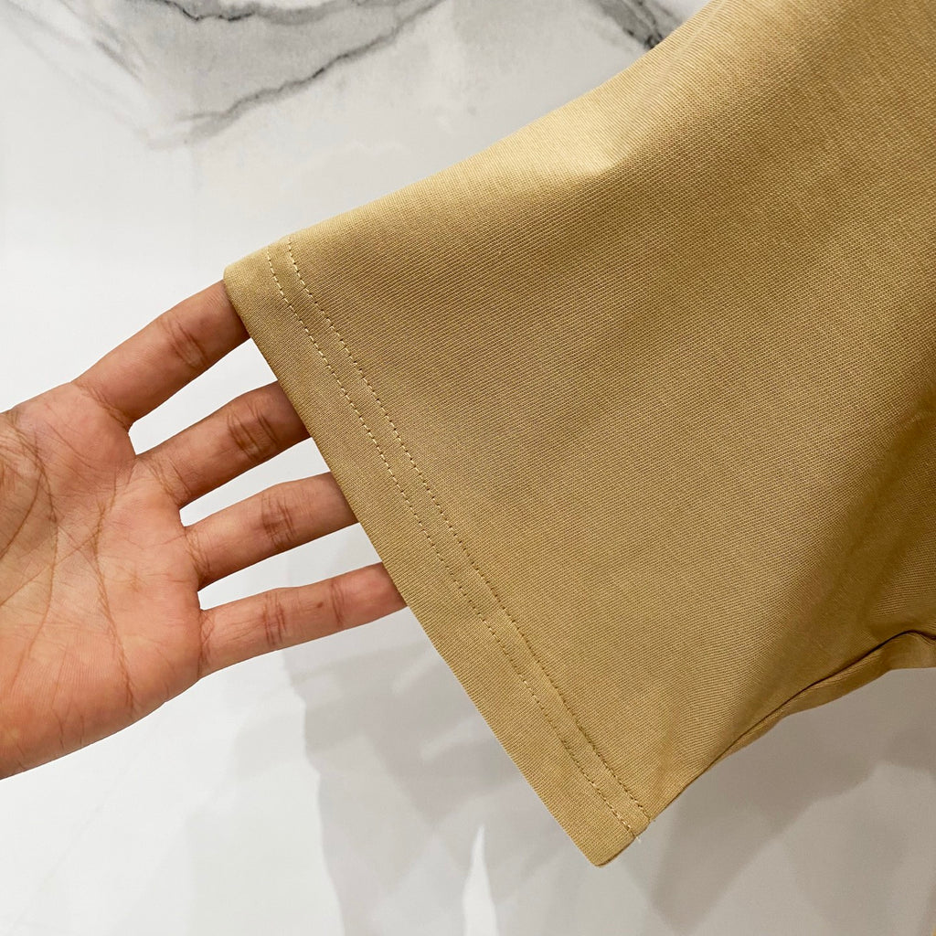 Tan T-shirt sleeve hem close-up showing stitching