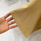 Tan T-shirt sleeve hem close-up showing stitching