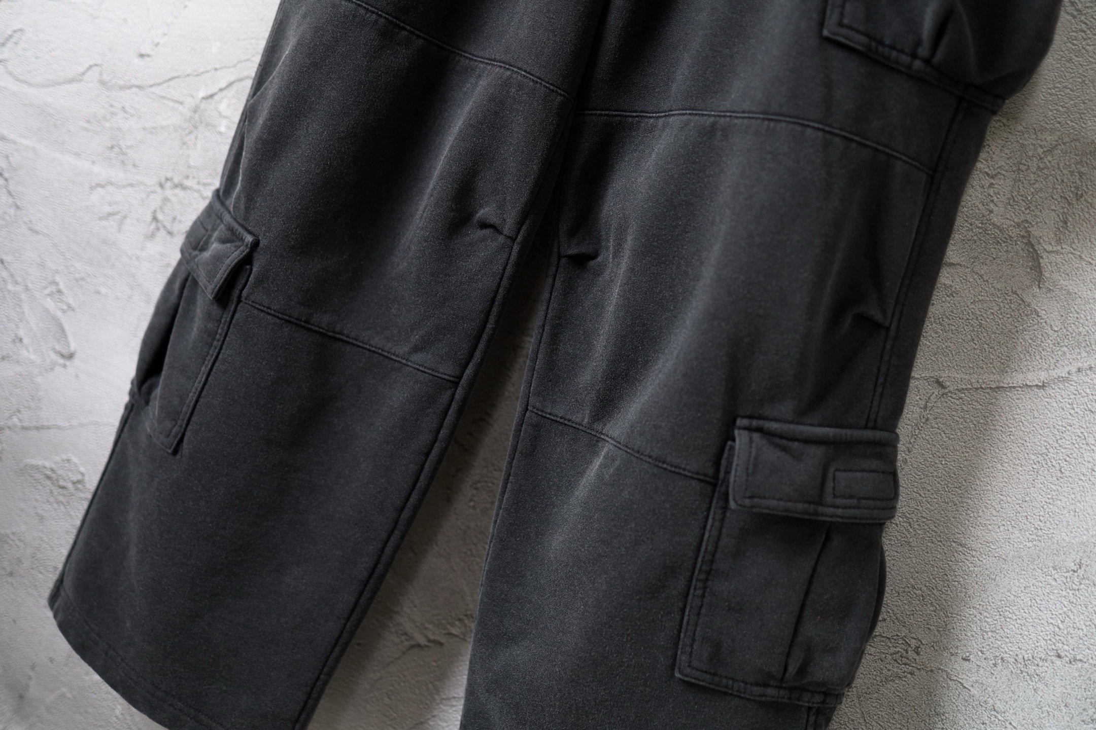 Dark gray cargo pants detail: flap pocket and side tab