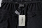Balenciaga pants hang tags on elastic waistband, printed labels visible on dark fabric