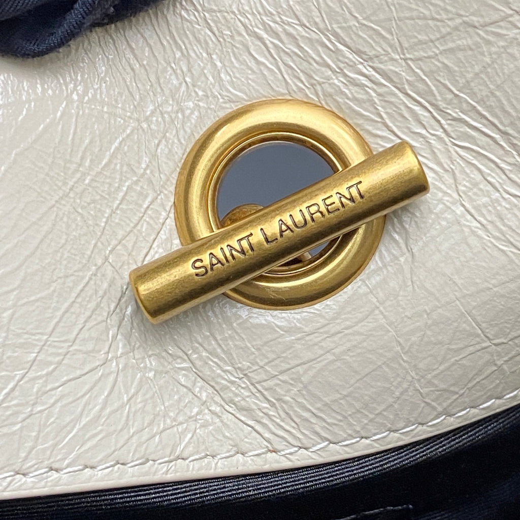 Gold clasp hardware engraved with SAINT LAUREN T on white leather