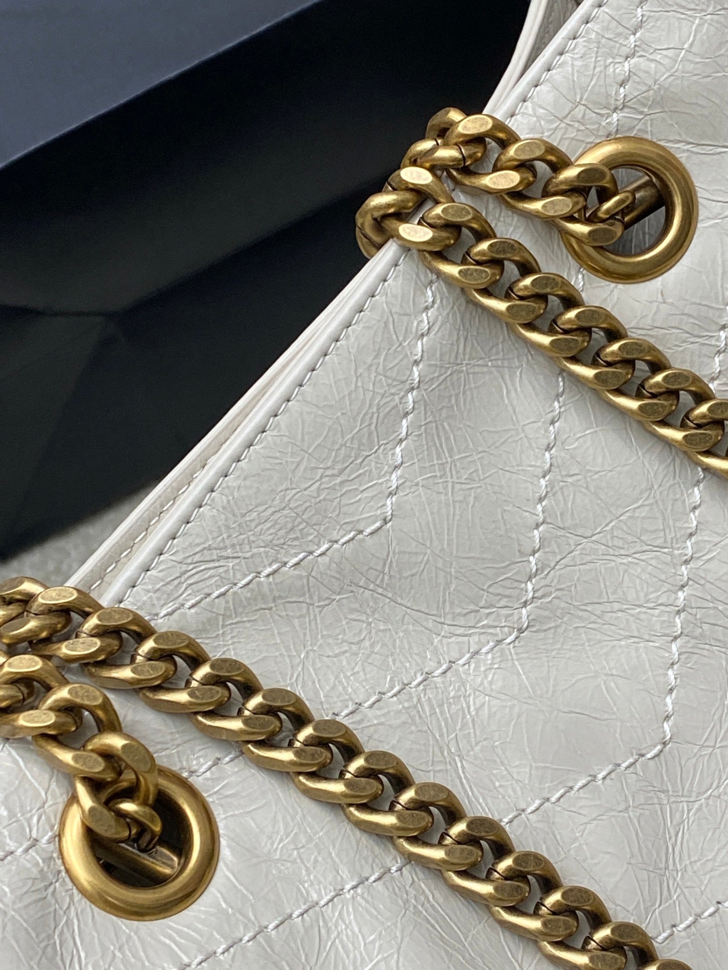 Gold chain strap and round ring hardware on white leather bag