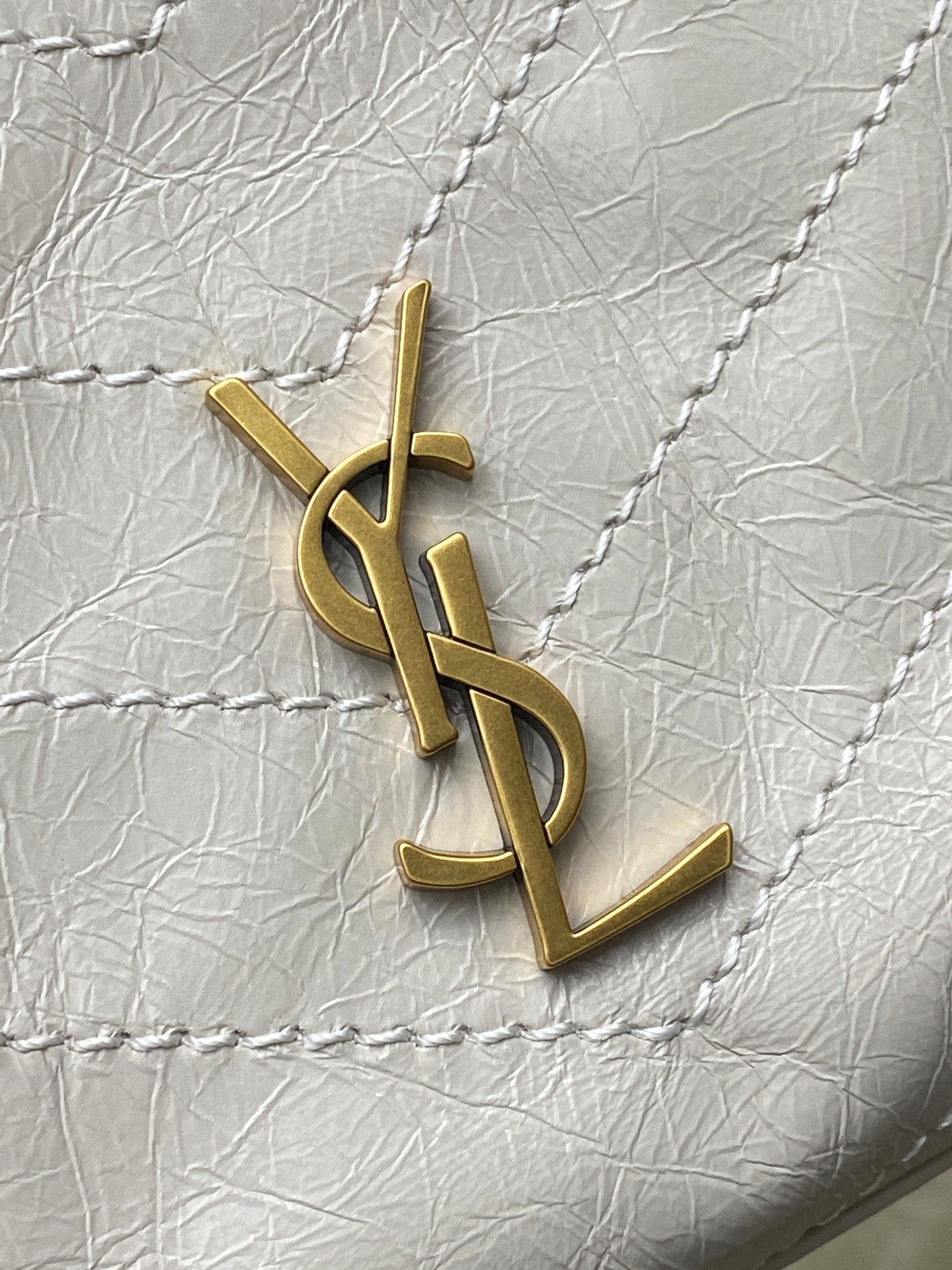 Gold YSL logo charm on white quilted leather bag