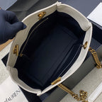 White bag opening with black lining, zipper, gold hardware, and gold chain strap