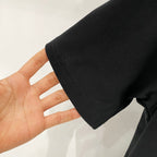Black T-shirt sleeve cuff held in hand, showing fabric texture
