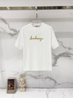 White short-sleeve T-shirt with gold logo text graphic on the chest
