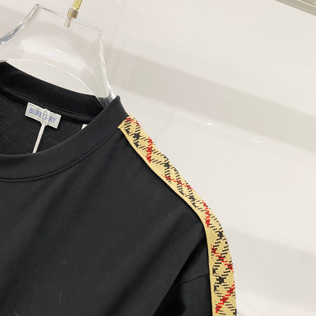 Black Burberry T-shirt shoulder close-up, multicolor trim stripe along seam.