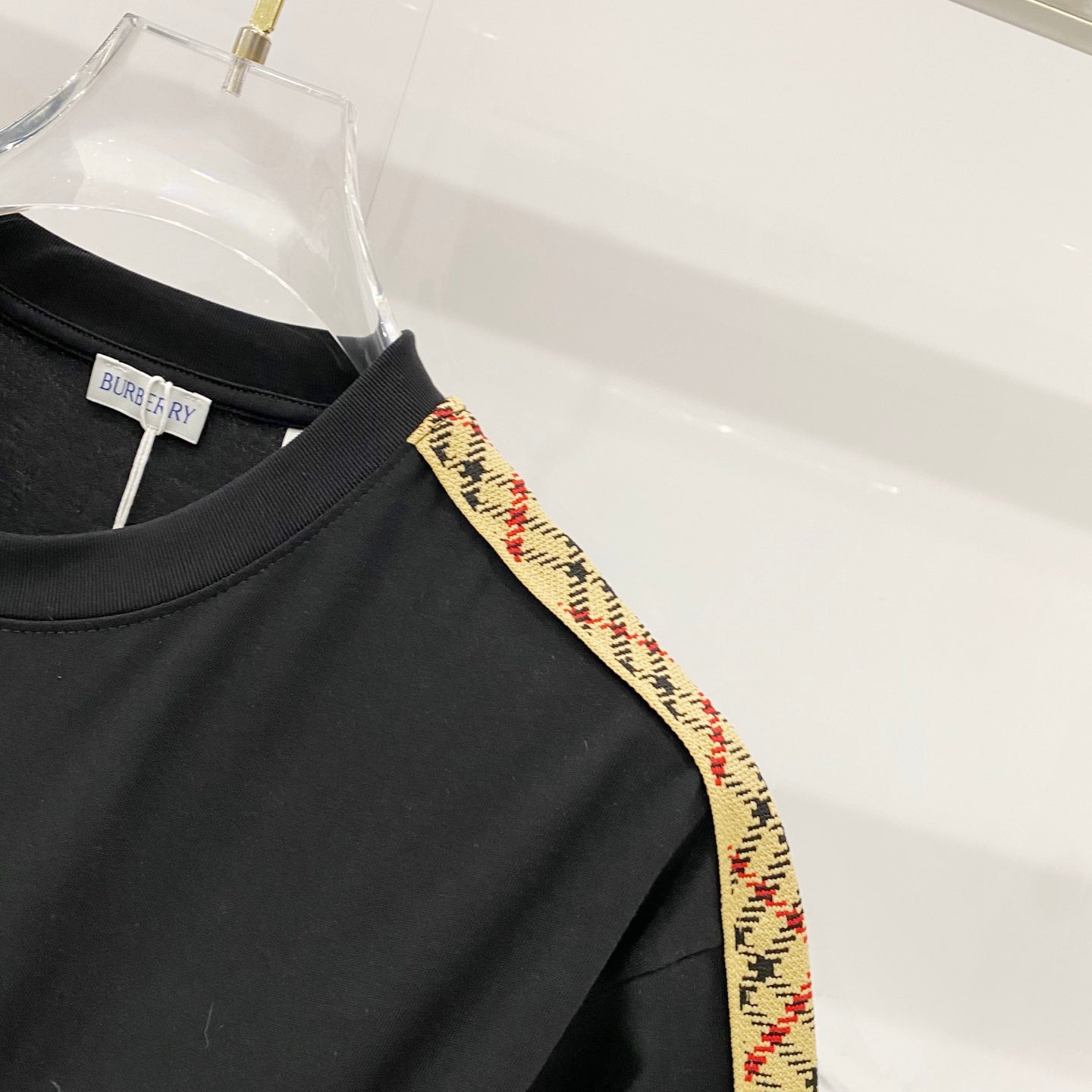 Black Burberry T-shirt shoulder close-up, multicolor trim stripe along seam.