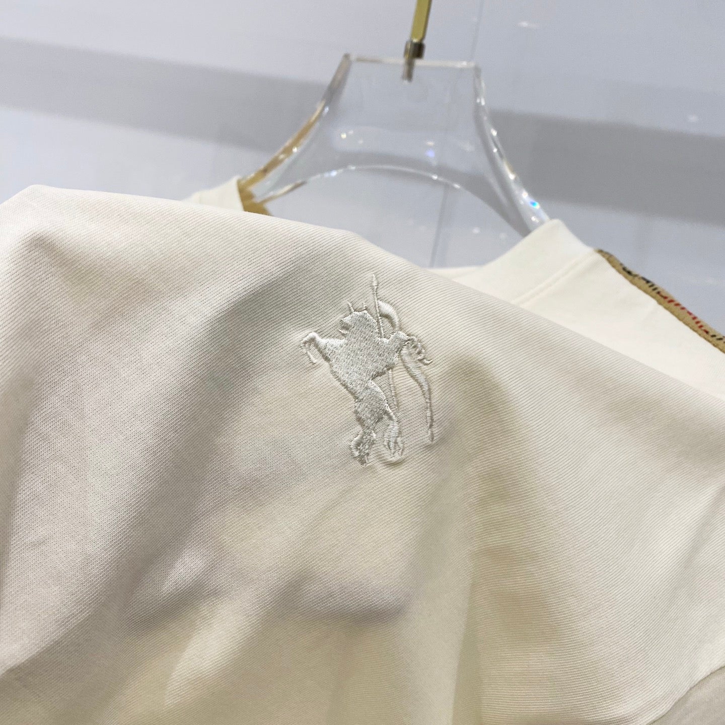 Cream T-shirt sleeve with raised horse logo embroidery
