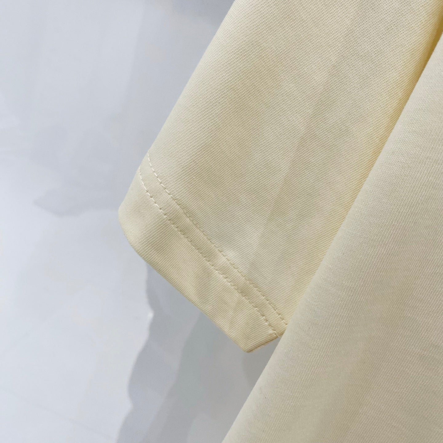 Cream T-shirt sleeve cuff with visible hem stitching