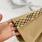 Mustard T-shirt sleeve cuff close-up with multicolor plaid trim, held in hand