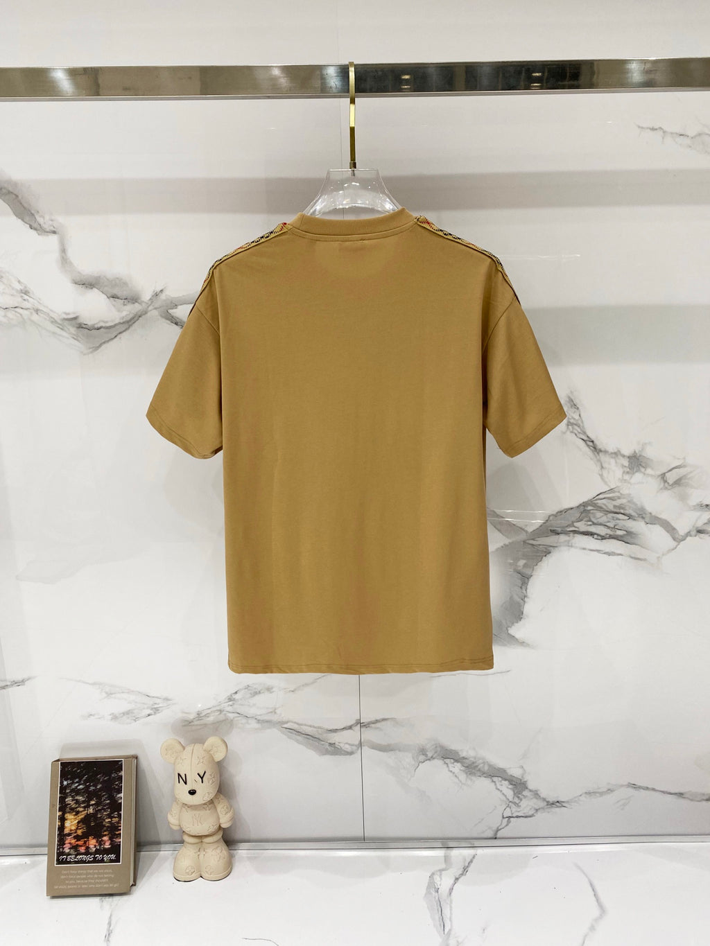 Mustard short-sleeve crewneck T-shirt back view on a clear hanger, plain design