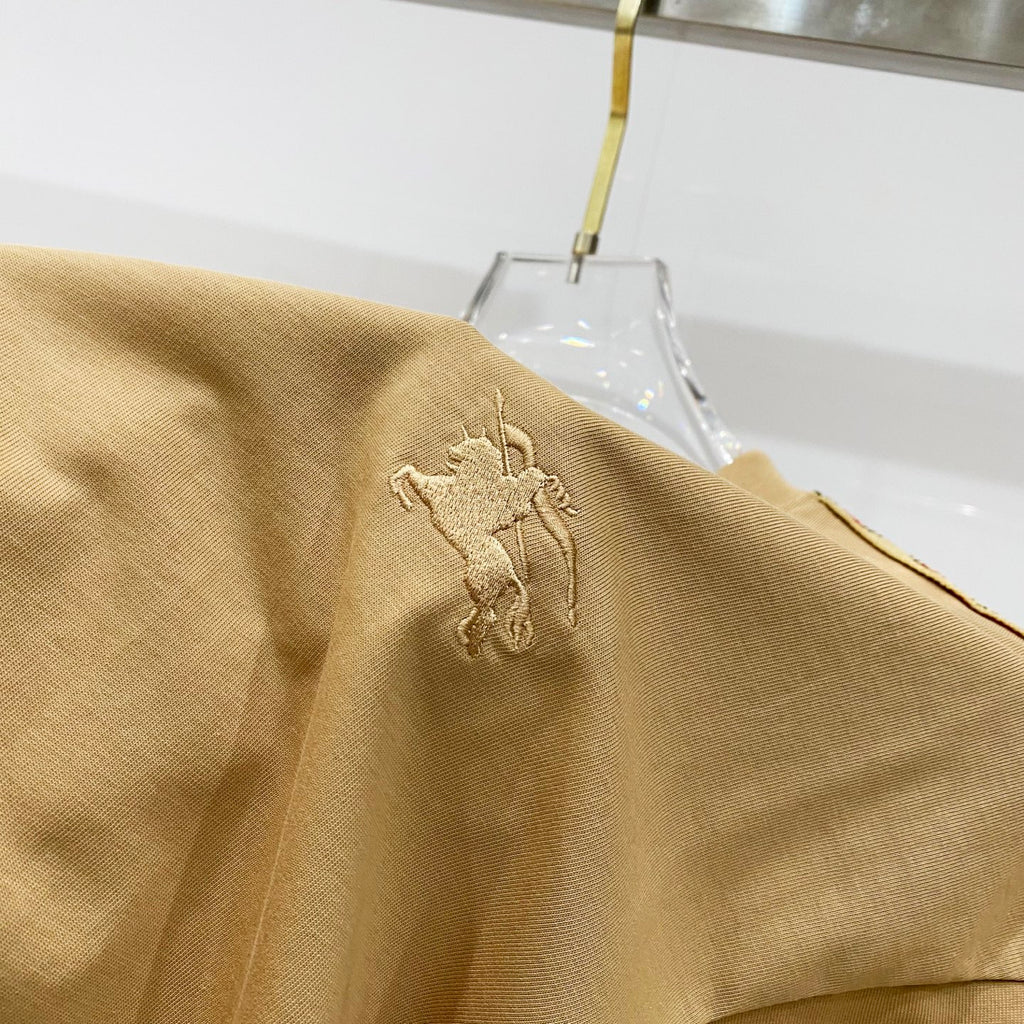 Mustard T-shirt fabric close-up with embroidered horse logo on the chest