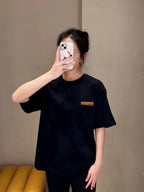 Dark short-sleeve top with chest pocket and small gold label