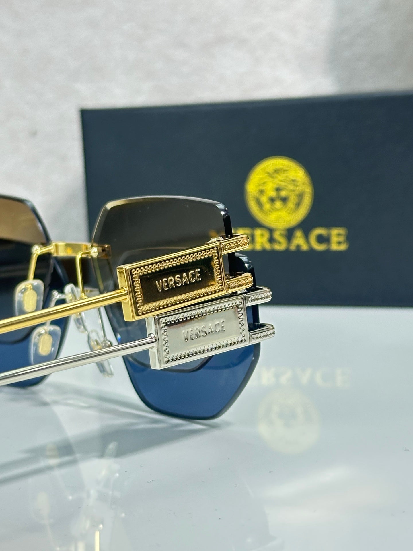Versace sunglasses with dark blue lenses and gold-tone frame, logo detail on temple