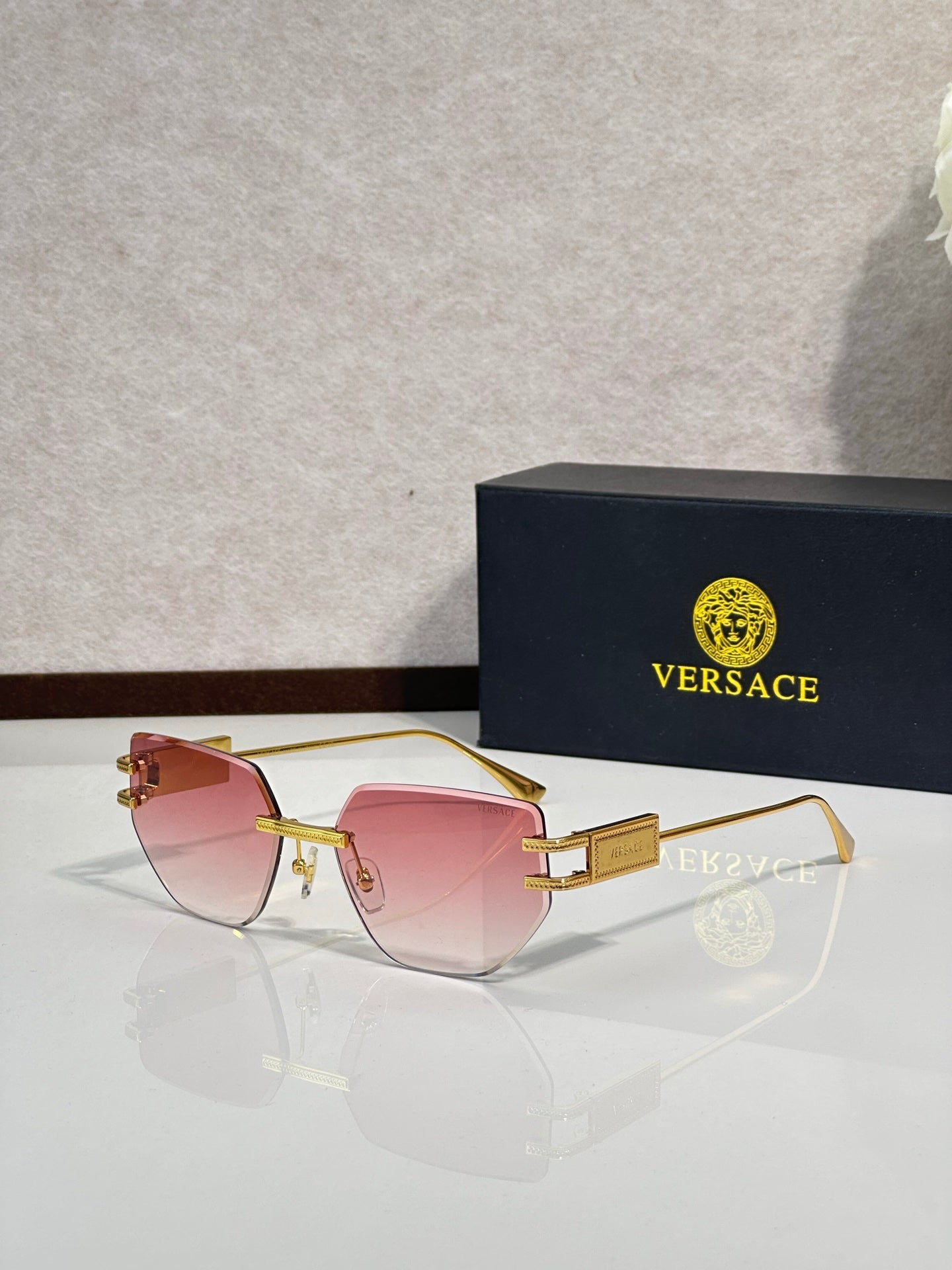 Versace eyeglasses with pink tinted lenses and gold-tone metal frame, rectangular shape