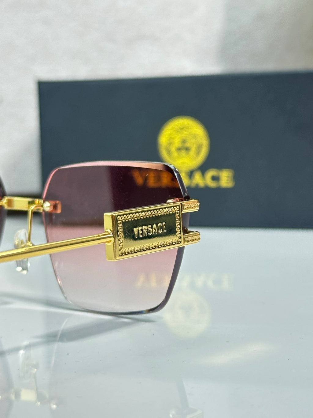Versace sunglasses close-up, gold frame with pink gradient tinted lens