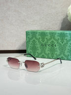 Gold-framed sunglasses with pink-tinted lenses and green temple accents