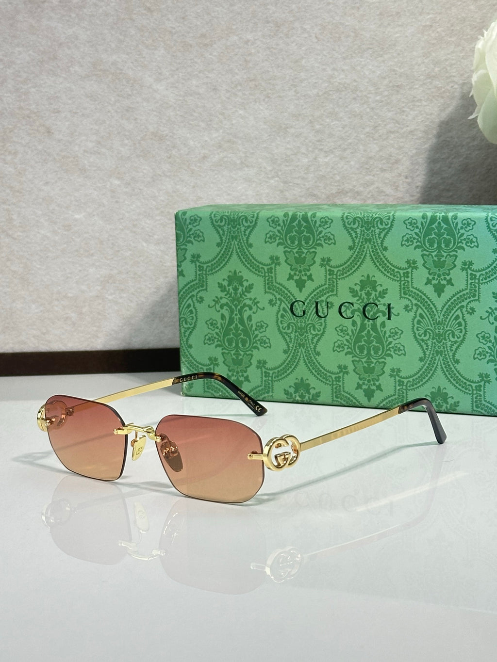 Gold-framed sunglasses with amber lenses and green temple accents