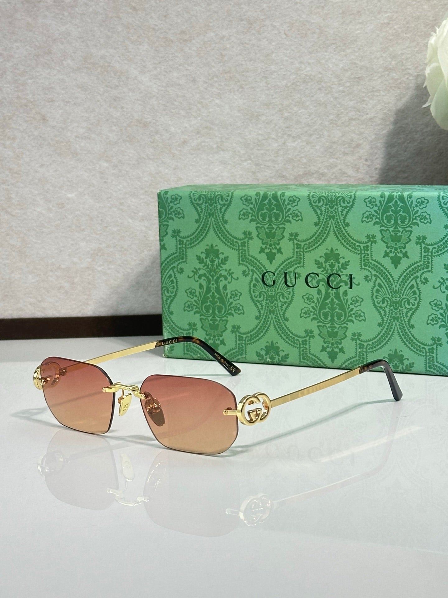 Gold-framed sunglasses with amber lenses and green temple accents