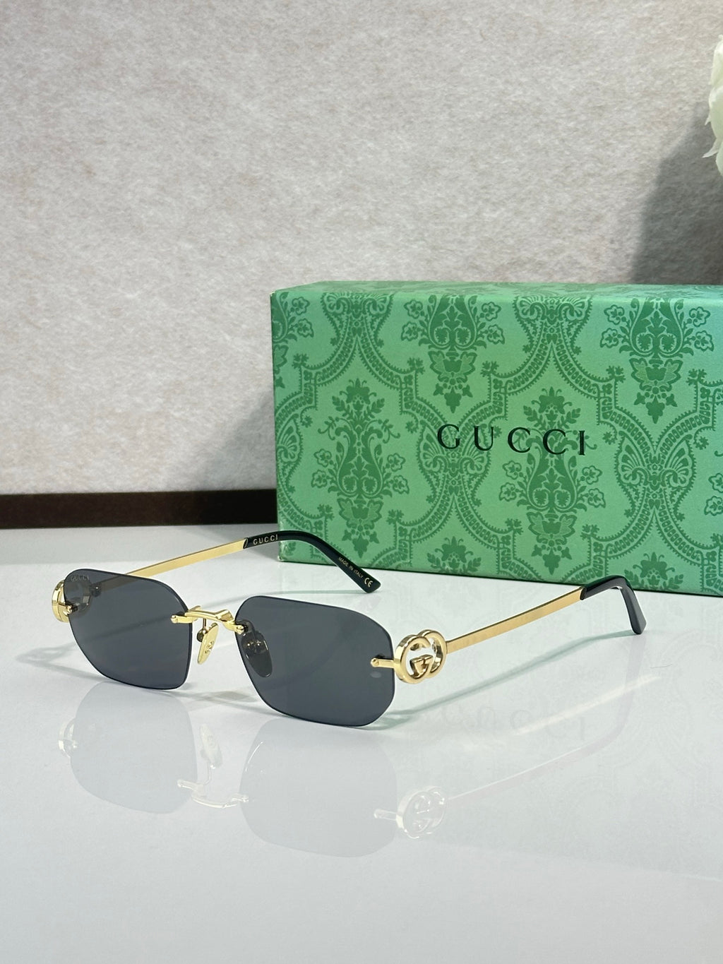 Gold-framed sunglasses with dark blue lenses and green temple accents