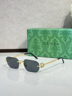 Gold-framed sunglasses with dark blue lenses and green temple accents