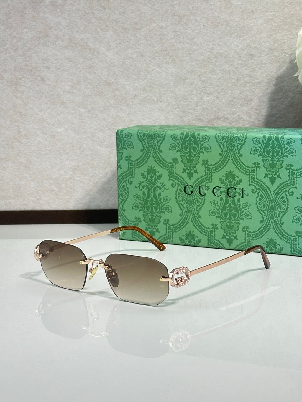 Gold-framed sunglasses with light brown lenses and green temple accents