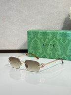 Gold-framed sunglasses with light brown lenses and green temple accents