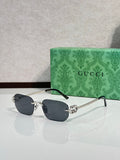 Gold-framed sunglasses with dark gray lenses and green temple accents