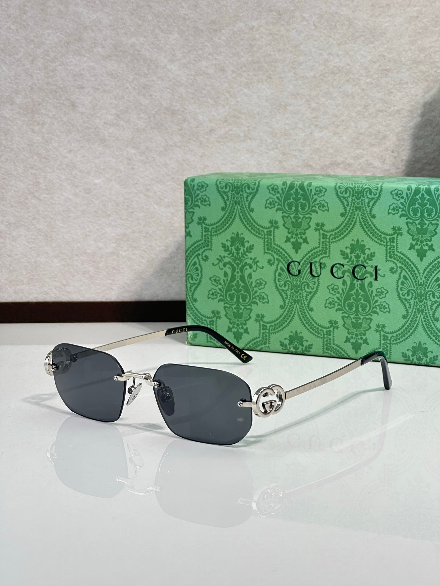Gold-framed sunglasses with dark gray lenses and green temple accents
