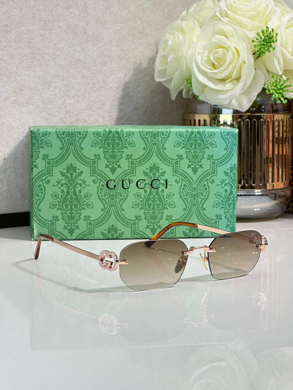 Gold-framed sunglasses with light gray lenses and brown-tinted tint
