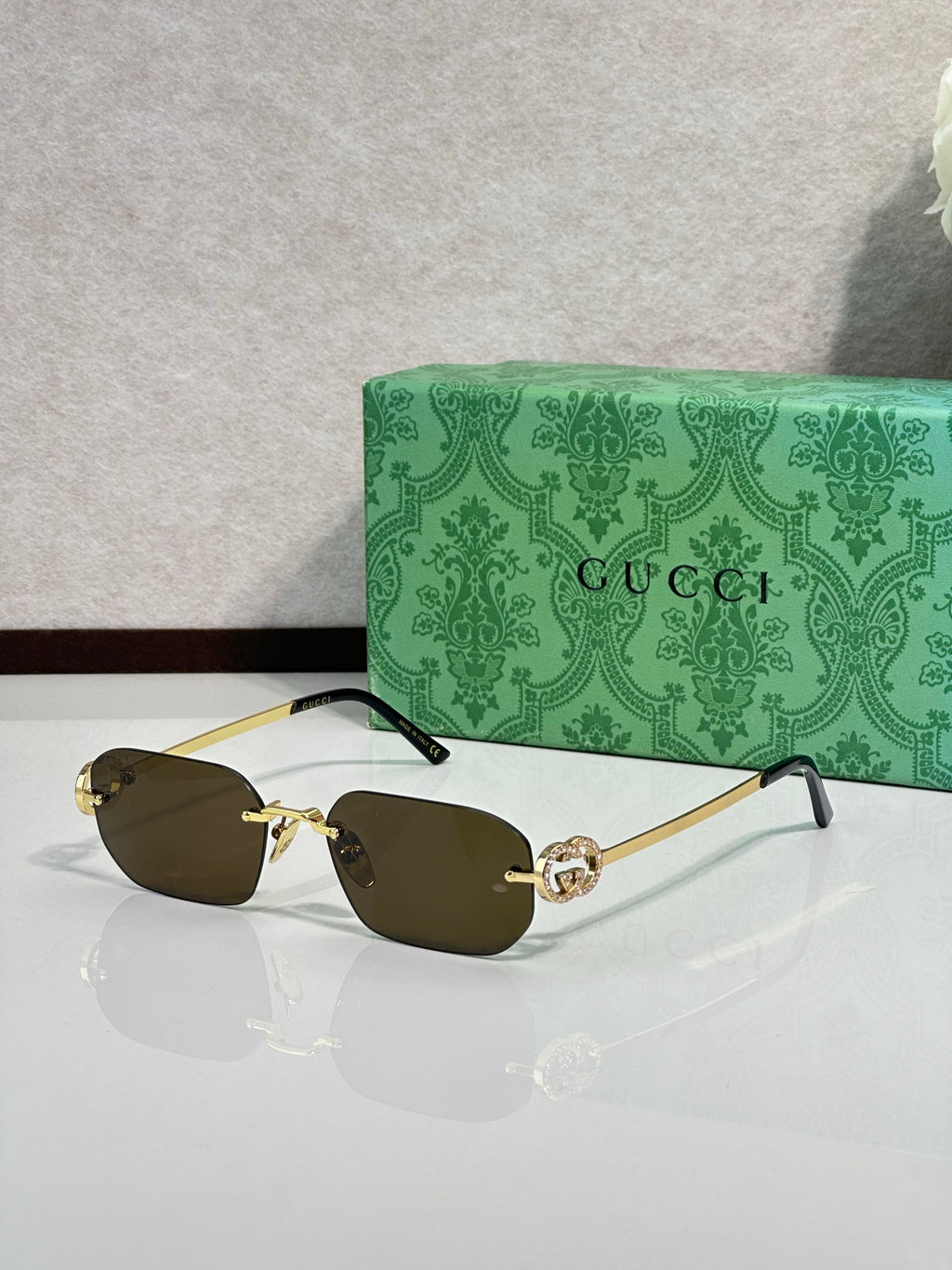 Gold-framed sunglasses with dark olive lenses and green temple accents