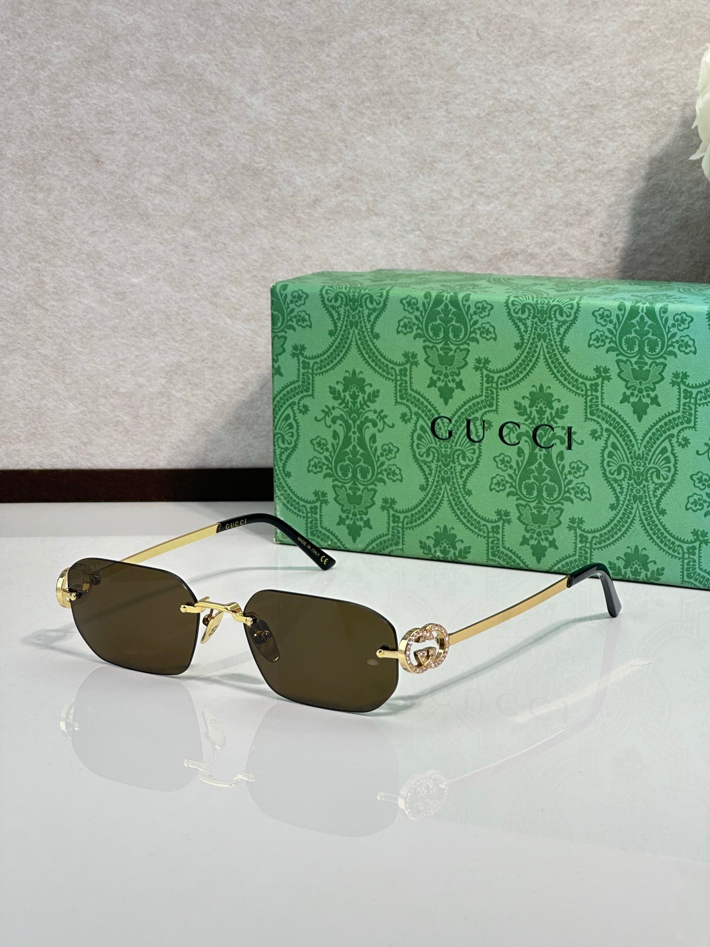 Gold-framed sunglasses with dark olive lenses and green temple accents