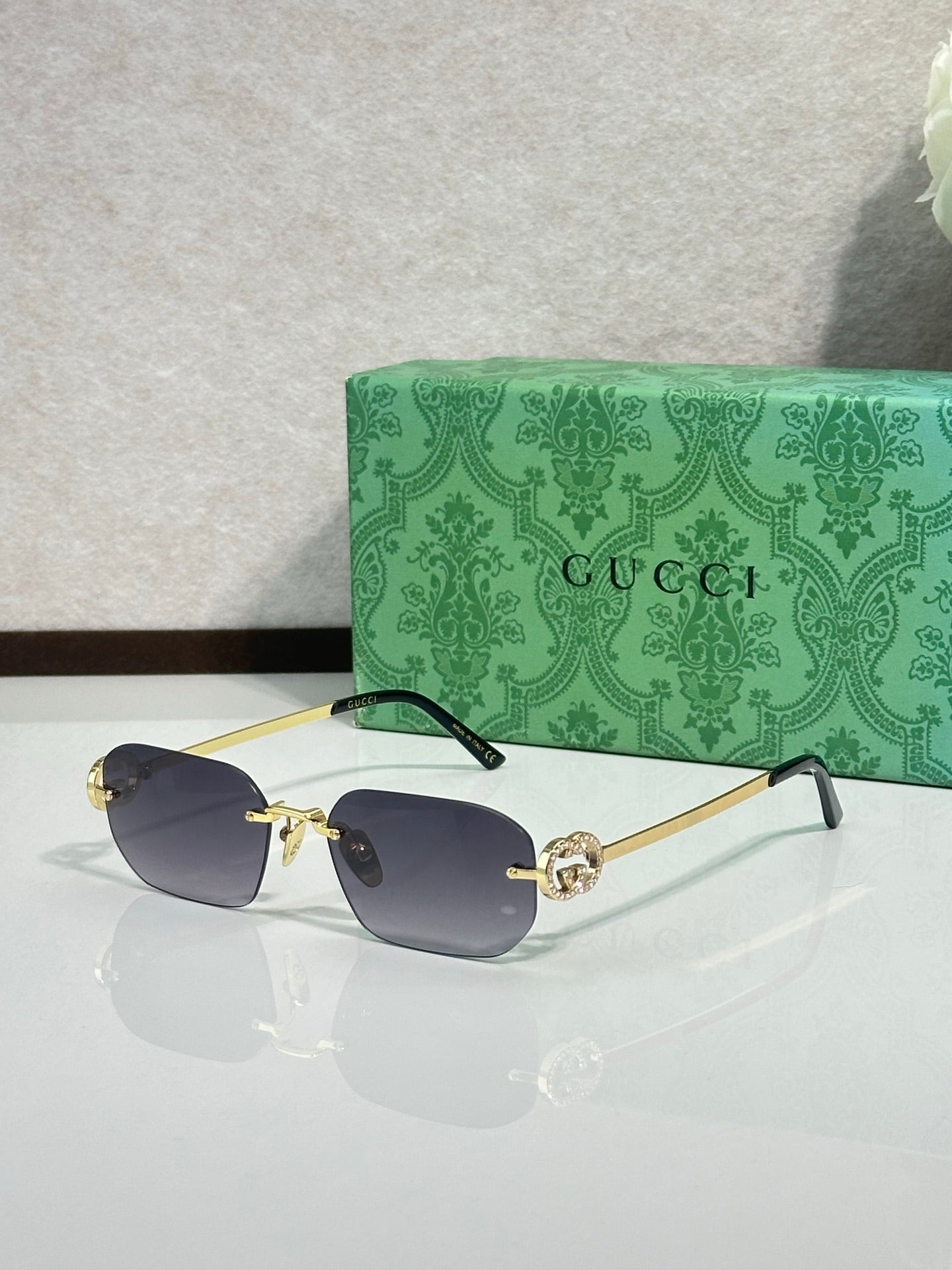 Gold-framed sunglasses with deep blue lenses and green temple accents