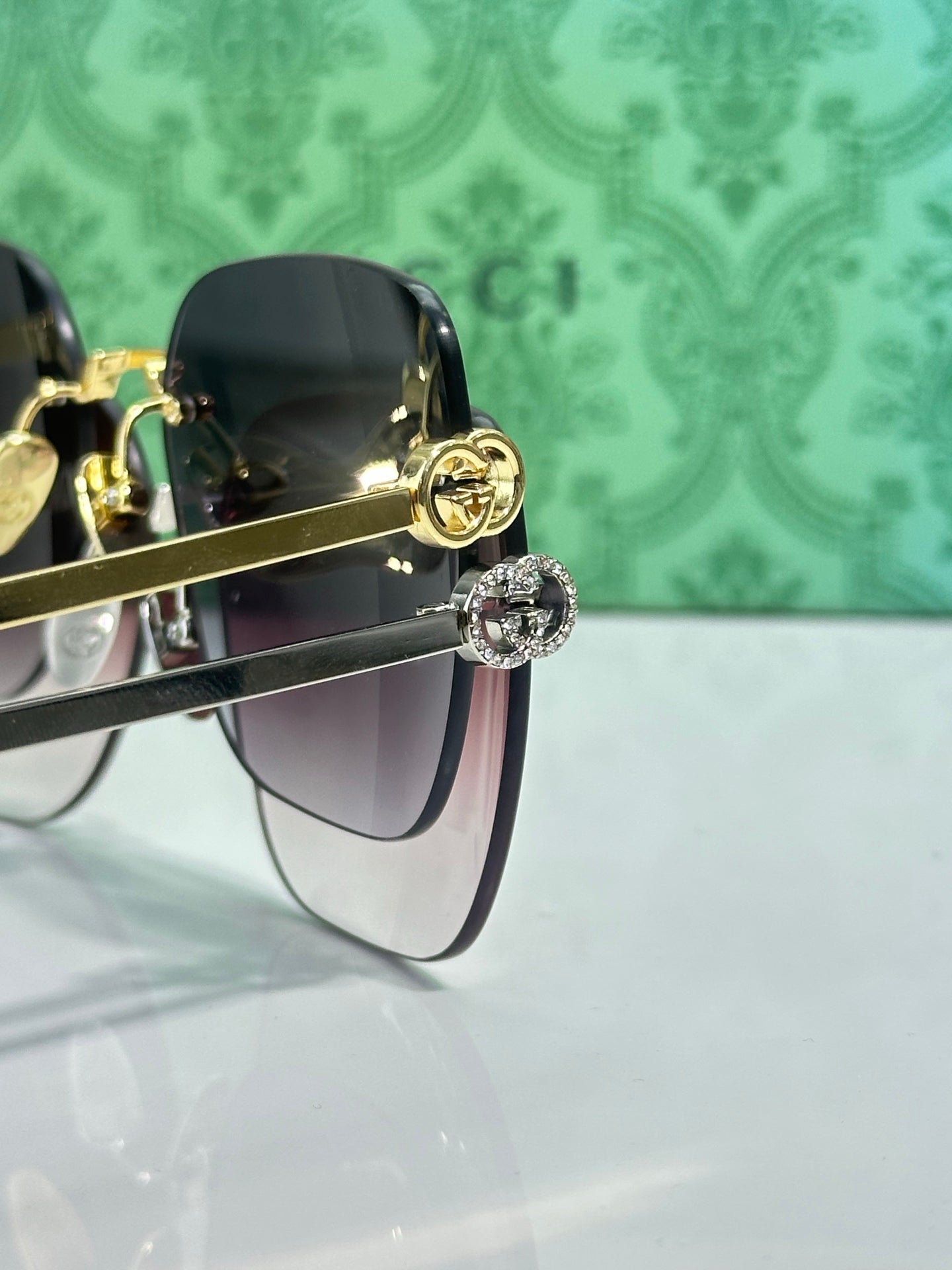 Gucci sunglasses close-up of dark lenses with gold-tone hinge and emblem detail