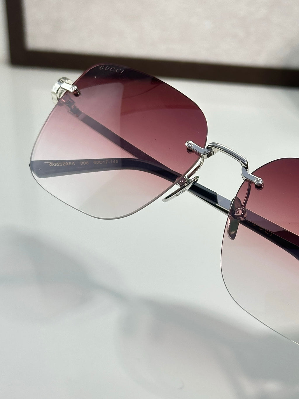 Gucci sunglasses close-up with burgundy tinted lens and metal bridge hardware