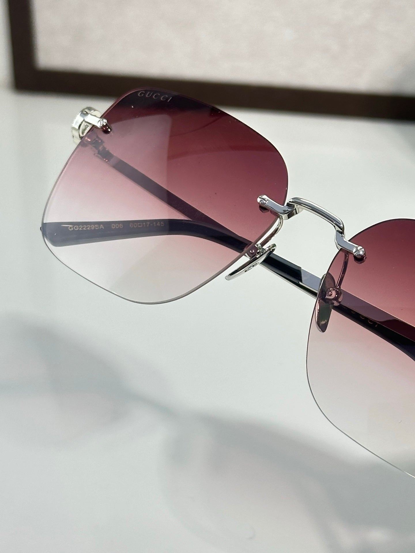 Gucci sunglasses close-up with burgundy tinted lens and metal bridge hardware