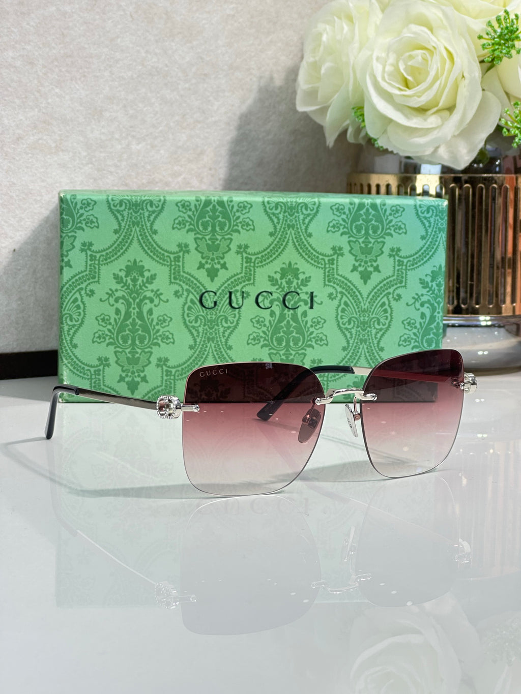 Gucci sunglasses with burgundy gradient lenses and gold-tone frame, angled view