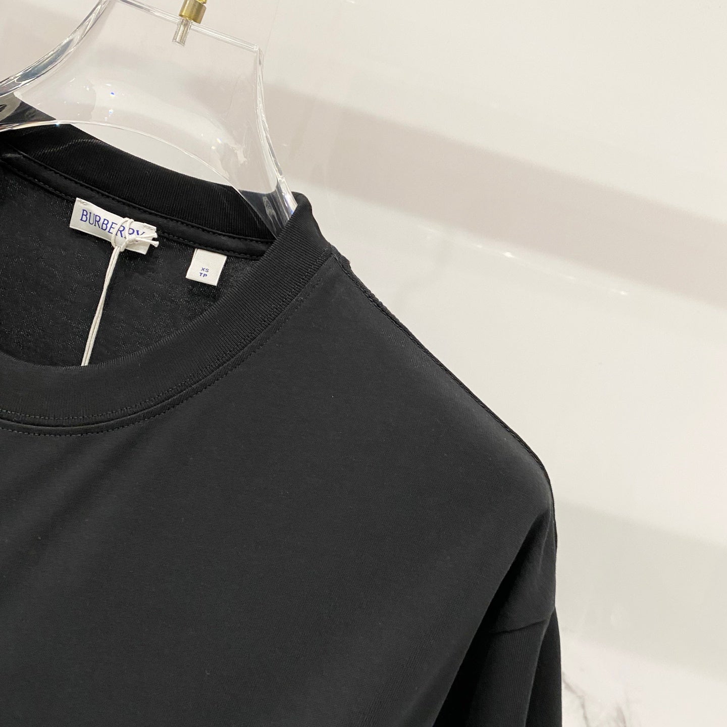 Black T-shirt front with crew neckline and hanging inner label