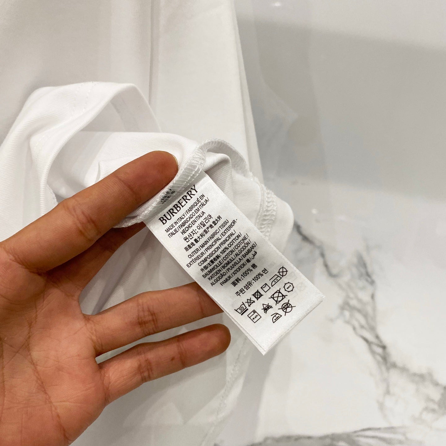 Burberry clothing care tag attached inside neck of white T-shirt