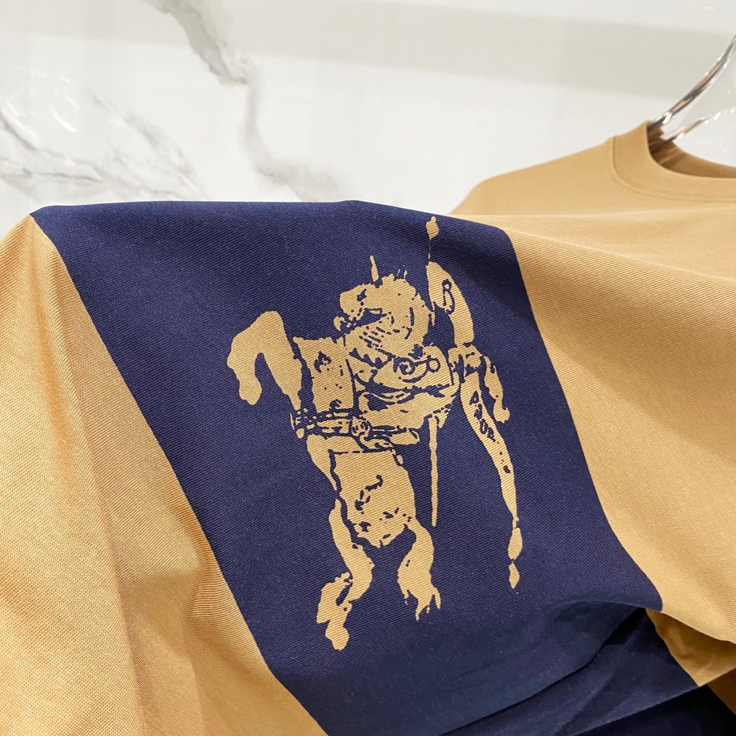 Tan T-shirt with navy panel and gold horse rider graphic