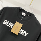 Black short-sleeve T-shirt with large white BURBERRY lettering and gold hang tag